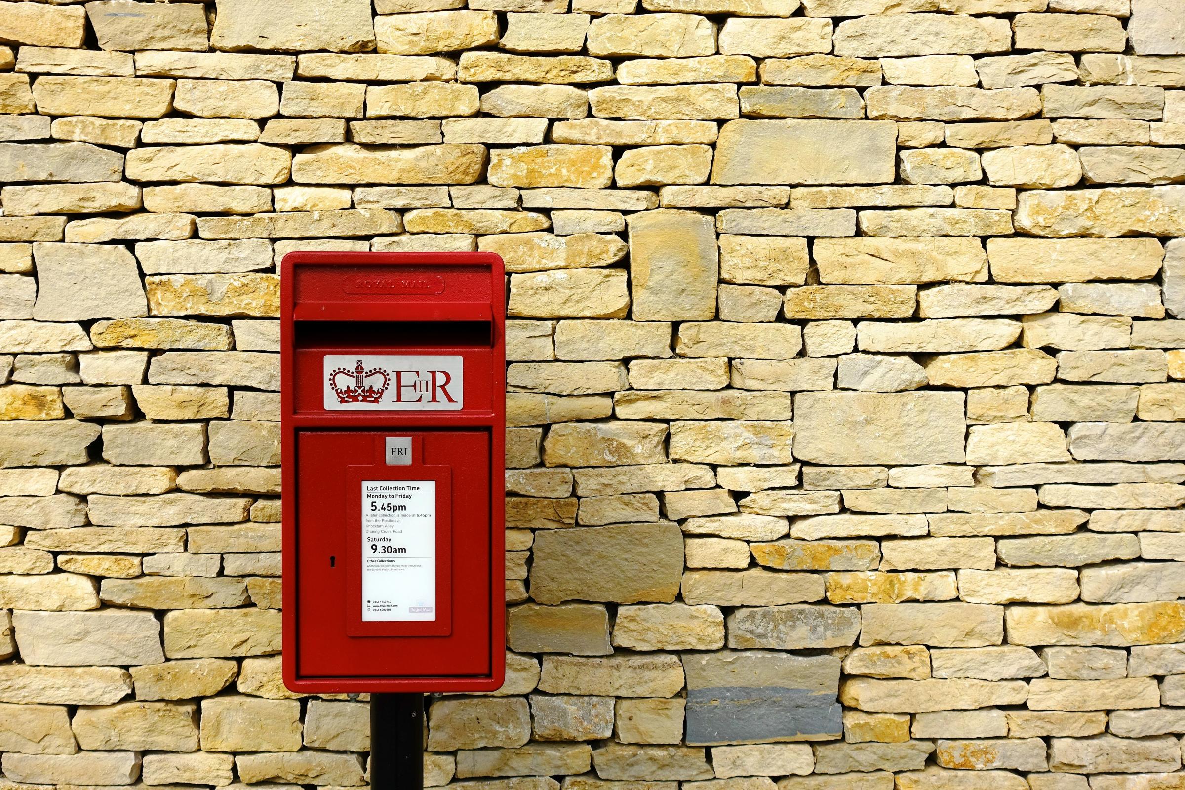 red british postbox in front of a wall